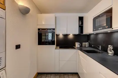 a kitchen with white cabinets and black counter tops at Apartment Winn, Alpes Travel, Central Chamonix, Sleeps 6 in Chamonix-Mont-Blanc