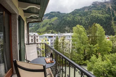a balcony with a table and chairs and mountains at Apartment Winn, Alpes Travel, Central Chamonix, Sleeps 6 in Chamonix-Mont-Blanc