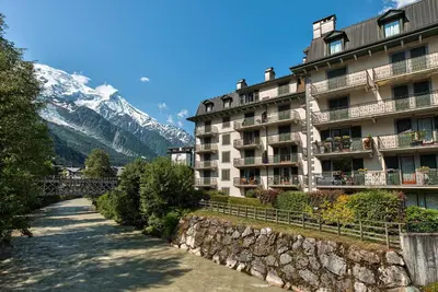 a building with a stone wall next to a mountain at Apartment Winn, Alpes Travel, Central Chamonix, Sleeps 6 in Chamonix-Mont-Blanc