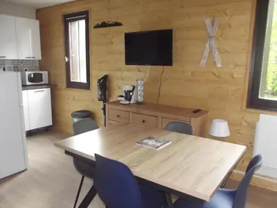 a dining room with a table and a television on the wall at studio familial 4 couchages in Arâches-la-Frasse