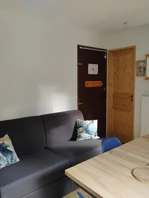 a living room with a couch and a door at studio familial 4 couchages in Arâches-la-Frasse
