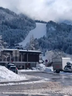 a snow covered road with a building and a river at studio familial 4 couchages in Arâches-la-Frasse