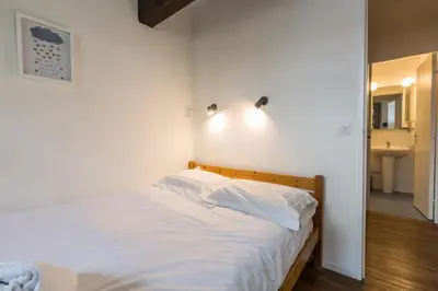 a bedroom with a bed with white sheets and a bathroom at Apartment Jonquille 3 - A Comfortable Chamonix Haven in Chamonix-Mont-Blanc