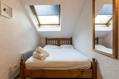 a small bed in a room with a mirror at Apartment Jonquille 3 - A Comfortable Chamonix Haven in Chamonix-Mont-Blanc