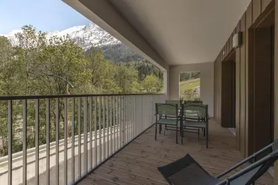 a balcony with a table and chairs and mountains at Le mazot de Kayla - Espace bien être, picine in Les Houches