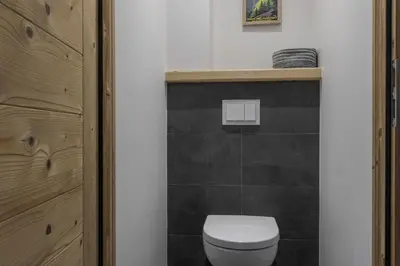 a bathroom with a white toilet and a black wall at Trabets 2 - Vue Montagne - 150m des Remontees in Les Houches