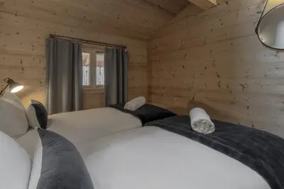 two beds in a room with wooden walls at Trabets 2 - Vue Montagne - 150m des Remontees in Les Houches