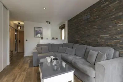 a living room with a gray couch and a brick wall at Tout Schuss - Centre St Gervais - Vue degagee in Saint-Gervais-les-Bains