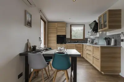 a kitchen with wooden cabinets and a table with chairs at Tout Schuss - Centre St Gervais - Vue degagee in Saint-Gervais-les-Bains