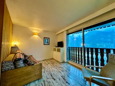 a bedroom with a balcony with a bed and a large window at appartement 4 personnes au coeur de la station des carroz d arâches in Arâches-la-Frasse