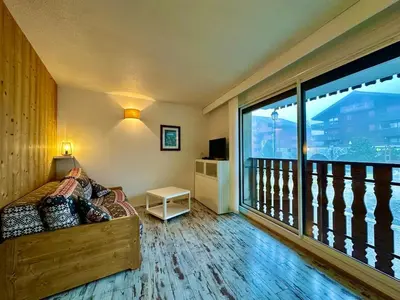 a room with a bed and a balcony with a large window at appartement 4 personnes au coeur de la station des carroz d arâches in Arâches-la-Frasse