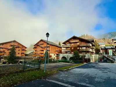 a large wooden building with a parking lot in front of it at appartement 4 personnes au coeur de la station des carroz d arâches in Arâches-la-Frasse