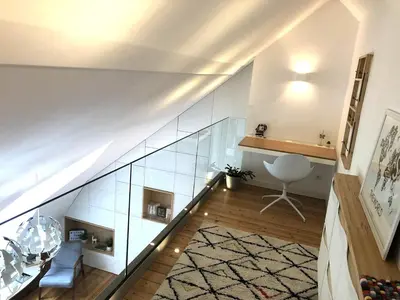 a staircase with glass walls and a chair in a room at Duplex avec vue Mont-Blanc, centre ville Chamonix in Chamonix-Mont-Blanc