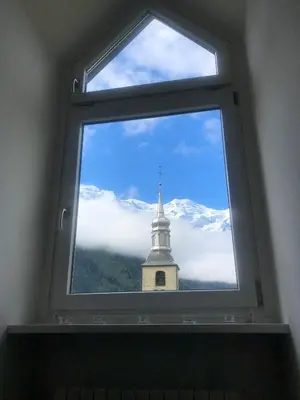 a window with a view of a clock tower at Duplex avec vue Mont-Blanc, centre ville Chamonix in Chamonix-Mont-Blanc