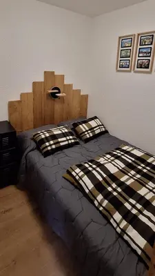 a bed with a wooden headboard in a bedroom at Cocon cozy, vue magique in Demi-Quartier