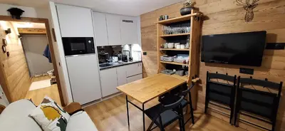 a small kitchen with a table and a tv in a room at Cocon cozy, vue magique in Demi-Quartier