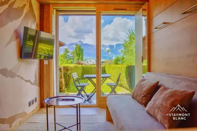 a living room with a couch and a table and a window at Nid douillet au pied du Tramway du MontBlanc à Saint-Gervais in Saint-Gervais-les-Bains