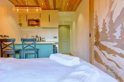 a bedroom with a bed and a kitchen with a counter at Nid douillet au pied du Tramway du MontBlanc à Saint-Gervais in Saint-Gervais-les-Bains