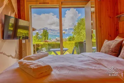 a bedroom with a bed and a large window at Nid douillet au pied du Tramway du MontBlanc à Saint-Gervais in Saint-Gervais-les-Bains