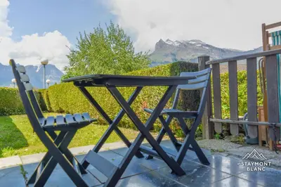 a blue chair sitting on a patio with mountains in the background at Nid douillet au pied du Tramway du MontBlanc à Saint-Gervais in Saint-Gervais-les-Bains