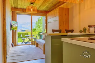 a kitchen with a view of a patio with a table at Nid douillet au pied du Tramway du MontBlanc à Saint-Gervais in Saint-Gervais-les-Bains