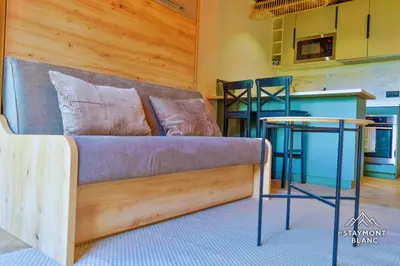 a couch and a table in a room with a kitchen at Nid douillet au pied du Tramway du MontBlanc à Saint-Gervais in Saint-Gervais-les-Bains