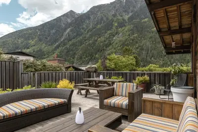 a patio with chairs and a table with mountains in the background at Chalet Zen - Sauna Hammam - Vue Mont-Blanc in Chamonix-Mont-Blanc