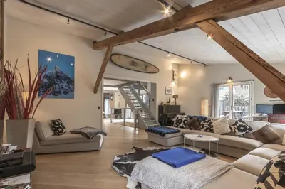 a living room with a couch and a staircase at Chalet Zen - Sauna Hammam - Vue Mont-Blanc in Chamonix-Mont-Blanc