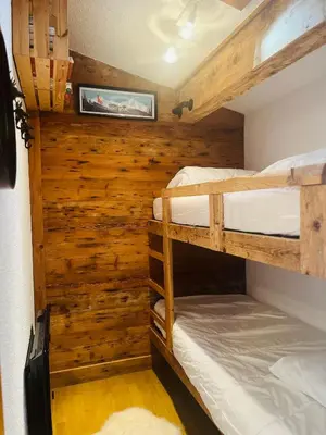 two bunk beds in a room with wooden walls at Elegant et cosy, Appt à la montagne in Combloux
