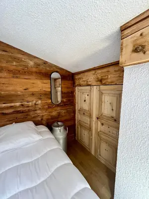 a bedroom with a white bed and wooden walls at Elegant et cosy, Appt à la montagne in Combloux