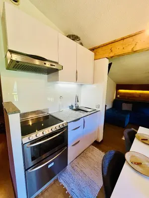 a kitchen with white cabinets and a stove top oven at Elegant et cosy, Appt à la montagne in Combloux