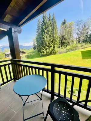 a table and a chair on a balcony with a view at Elegant et cosy, Appt à la montagne in Combloux