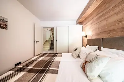 a bedroom with a white bed with a wooden wall at Apartment Cerna Les Houches - by EMERALD STAY in Les Houches