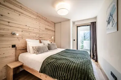 a bedroom with a wooden accent wall and a bed at Apartment Omas Les Houches - by EMERALD STAY in Les Houches