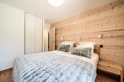 a bedroom with a wooden accent wall and a bed at Apartment Omas Les Houches - by EMERALD STAY in Les Houches