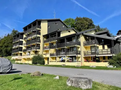 a yellow apartment building with balconies on a street at Les Airelles 402 in Arâches-la-Frasse