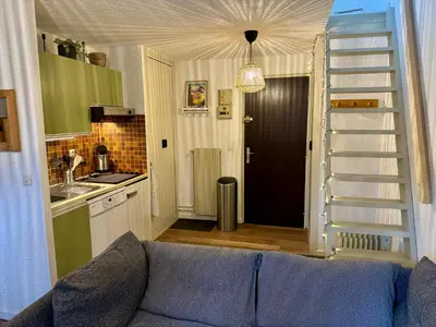 a living room with a blue couch and a kitchen at Les Airelles 402 in Arâches-la-Frasse