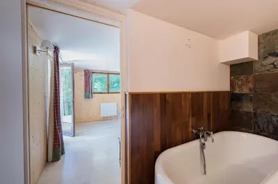 a bath tub in a bathroom with a wooden wall at Chalet l'Arba - Ecrin à la croisée des stations in Cordon