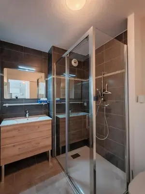 a bathroom with a shower and a sink and a mirror at Appartement avec jardin in Saint-Gervais-les-Bains