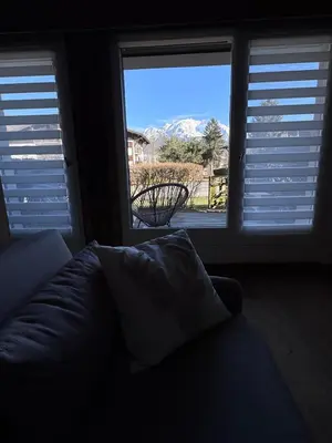 a living room with a couch and two large windows at Joli studio avec terrasse in Sallanches