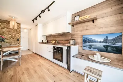 a kitchen with a large flat screen tv on a wall at Apartment Houchma Les Houches - by EMERALD STAY in Les Houches