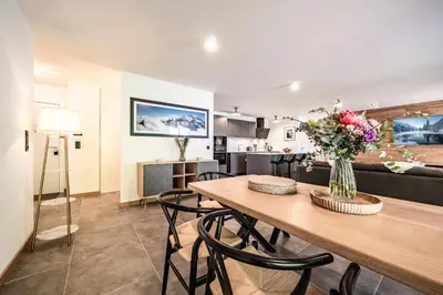 a dining room and living room with a table and flowers at Apartment Mathilde Les Houches - by EMERALD STAY in Les Houches
