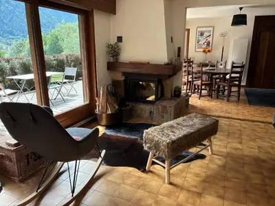 a living room with a fireplace and a table and chairs at 3 Bed Apartment with Private Terrace, Communal Pool, Mont Blanc Views in Saint-Gervais-les-Bains