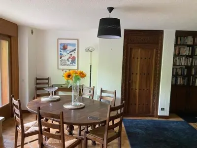 a dining room table with a vase of flowers on it at 3 Bed Apartment with Private Terrace, Communal Pool, Mont Blanc Views in Saint-Gervais-les-Bains