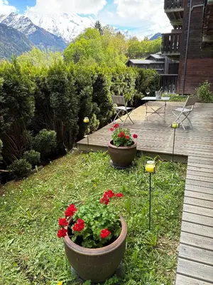 two pots of flowers in a yard with mountains at 3 Bed Apartment with Private Terrace, Communal Pool, Mont Blanc Views in Saint-Gervais-les-Bains