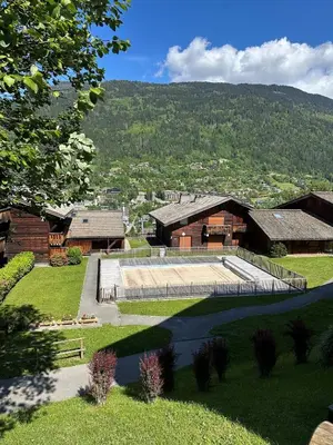a view of a building with mountains in the background at 3 Bed Apartment with Private Terrace, Communal Pool, Mont Blanc Views in Saint-Gervais-les-Bains
