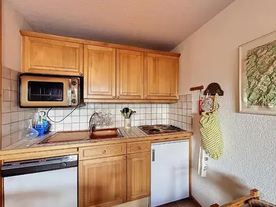 a kitchen with wooden cabinets and a sink and a microwave at Appartement proche village, accès ski bus, vue Mont Blanc - FR-1-560-163 in Combloux