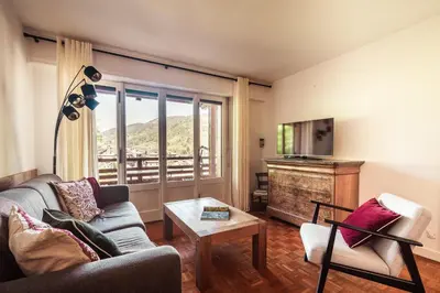 a living room with a couch and a television at Le Central - In the heart of Megève in Megève