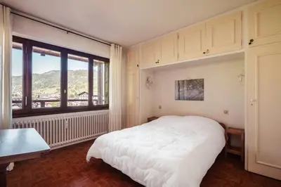 a bedroom with a white bed and a large window at Le Central - In the heart of Megève in Megève