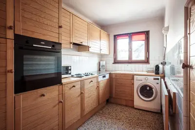 a kitchen with wooden cabinets and a washer and dryer at Le Central - In the heart of Megève in Megève
